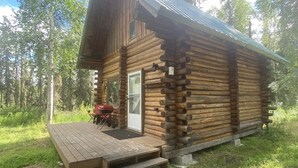 Eine Blockhütte mit einer Holzdielenveranda und einer Tür, die auf eine überdachte Veranda führt.