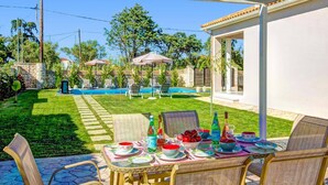 Um quintal com piscina, área de refeições ao ar livre e cadeiras de descanso.