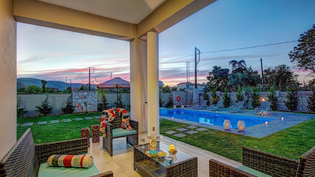Espaço ao ar livre coberto com piscina, mobiliário de vime e parede de pedra.