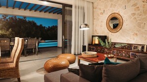 Una sala de estar moderna con vista a una piscina, muebles de mimbre y una pared de piedra.