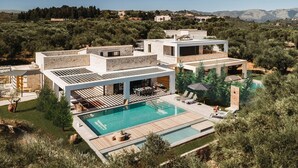 Una villa moderna con piscina, mobiliario exterior y vistas del paisaje circundante.