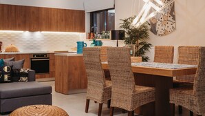 Una cocina moderna con armarios de madera, un comedor con sillas de mimbre y una isla central.