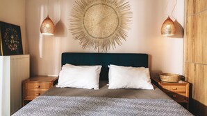 A neatly arranged bedroom with a large bed, two bedside tables, and a wall-mounted circular decorative piece. - Villa Tiare 2 by Villa Plus (Ionian Islands)