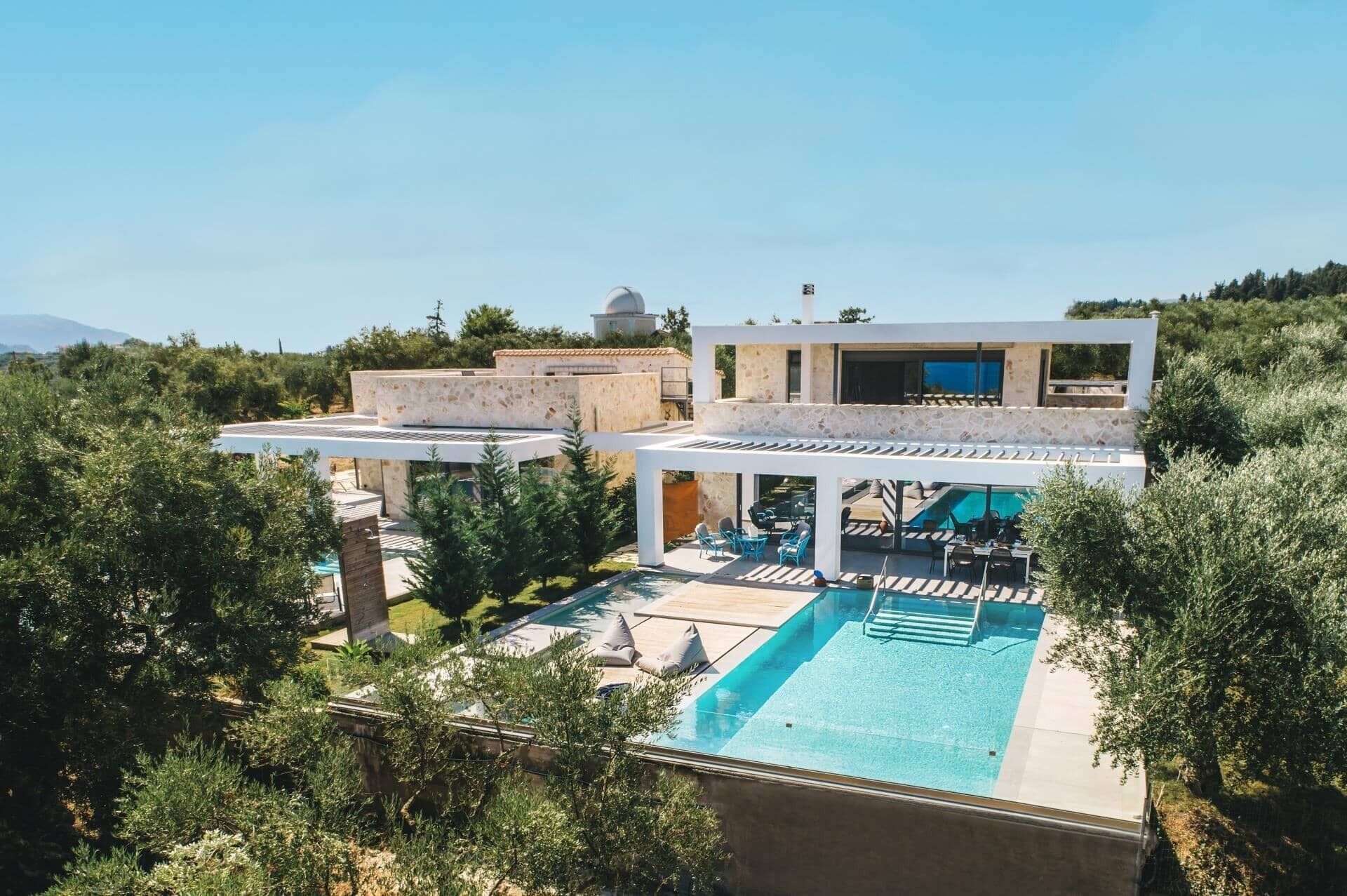Una villa moderna con piscina, area relax esterna e vista sul paesaggio circostante.