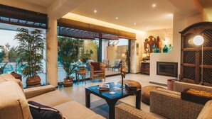 A spacious living room with a large window, comfortable seating, a fireplace, and a view of the outdoors. - Villa Tiare 2 by Villa Plus (Ionian Islands)