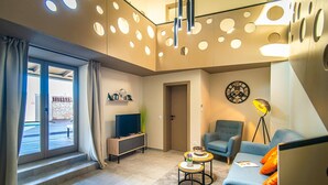 Ein modernes Wohnzimmer mit großem Fenster, einer Couch, einem Fernseher und einer Lampe.