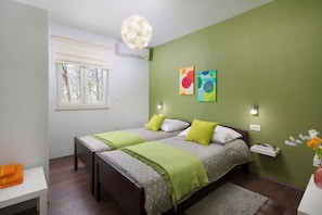 A bedroom with two beds, a window with blinds, a hanging light fixture, and artwork on the wall. - Villa Vivian by Villa Plus (Kringa)