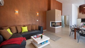 Un salon moderne comprenant un canapé, une table basse, une cheminée, un coin repas et une cuisine.