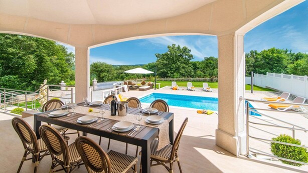 Une terrasse extérieure avec une piscine, une table à manger et des chaises.