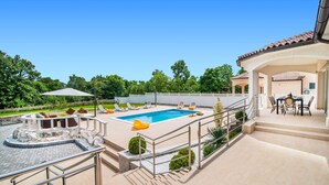 Un espace piscine comprenant des chaises longues, un jacuzzi et une terrasse avec une table et des chaises.