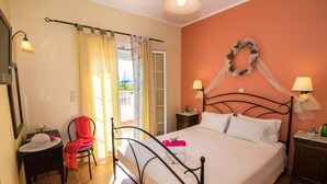 Un dormitorio con cama, mesita de noche, silla, lámpara y vistas al exterior.