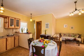 Un coin repas avec une table mise pour le petit-déjeuner, une cuisine avec des meubles en bois et un salon avec un canapé et une table basse.