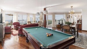 Amplia sala de estar con mesa de billar, asientos cómodos y grandes ventanales con vistas.