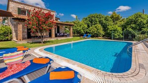 A swimming pool with lounge chairs and a stone building with a garden. - Villa Rizolia Enea by Villa Plus (Koridallos)