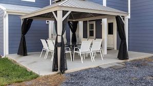 A covered patio with a table and chairs, a door, and a window. - The Sterling- walk to everything Luray has to offer! Chef available (Luray)
