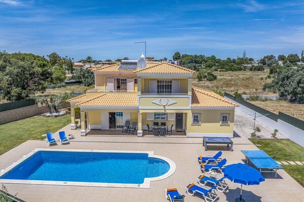 A two-story house with a swimming pool, outdoor seating, and a garden.