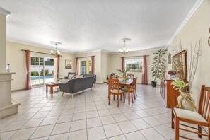 A spacious living area with a dining table, chairs, a sofa, and a ceiling fan.