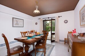 Enjoy meals in this dining area with a table for four, a chandelier, and a door leading to an outdoor space.