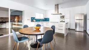 A modern kitchen with white cabinets, a stainless steel refrigerator, and a blue tiled backsplash. - Villa Terre Des Vins by Villa Plus (Portel-des-Corbières)