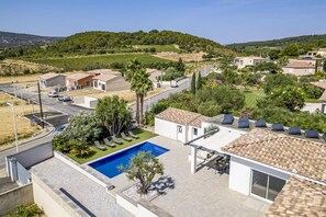 A residential area with a swimming pool, a road, and houses with solar panels.