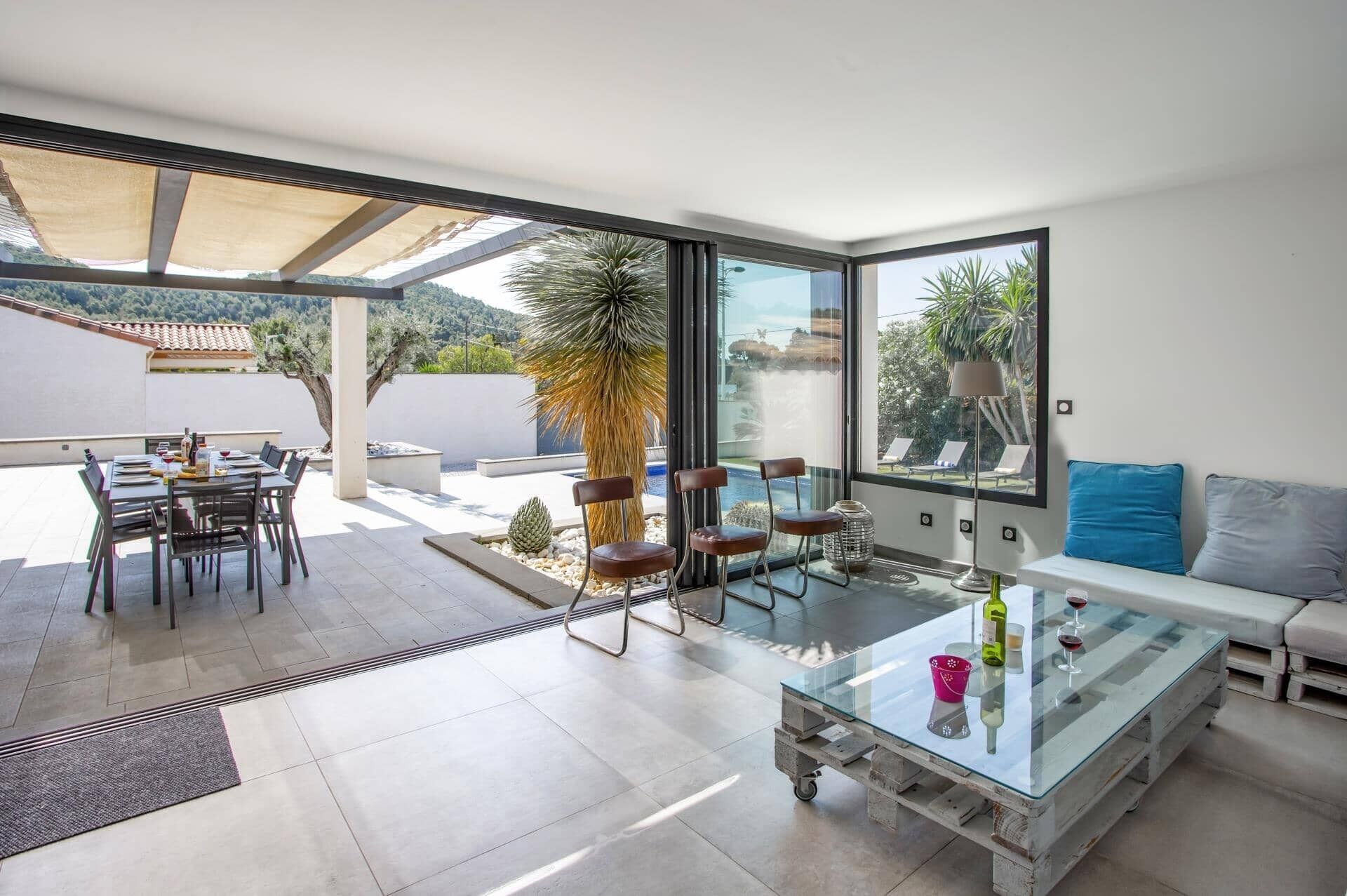 A modern living room with a glass coffee table, a sofa, and a dining area with chairs and a table.
