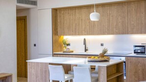 Una cocina moderna con armarios de madera, encimera blanca y una isla central con sillas.