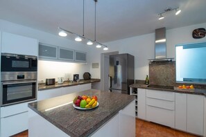Een moderne keuken met inbouwapparatuur, een granieten aanrechtblad en een fruitschaal.