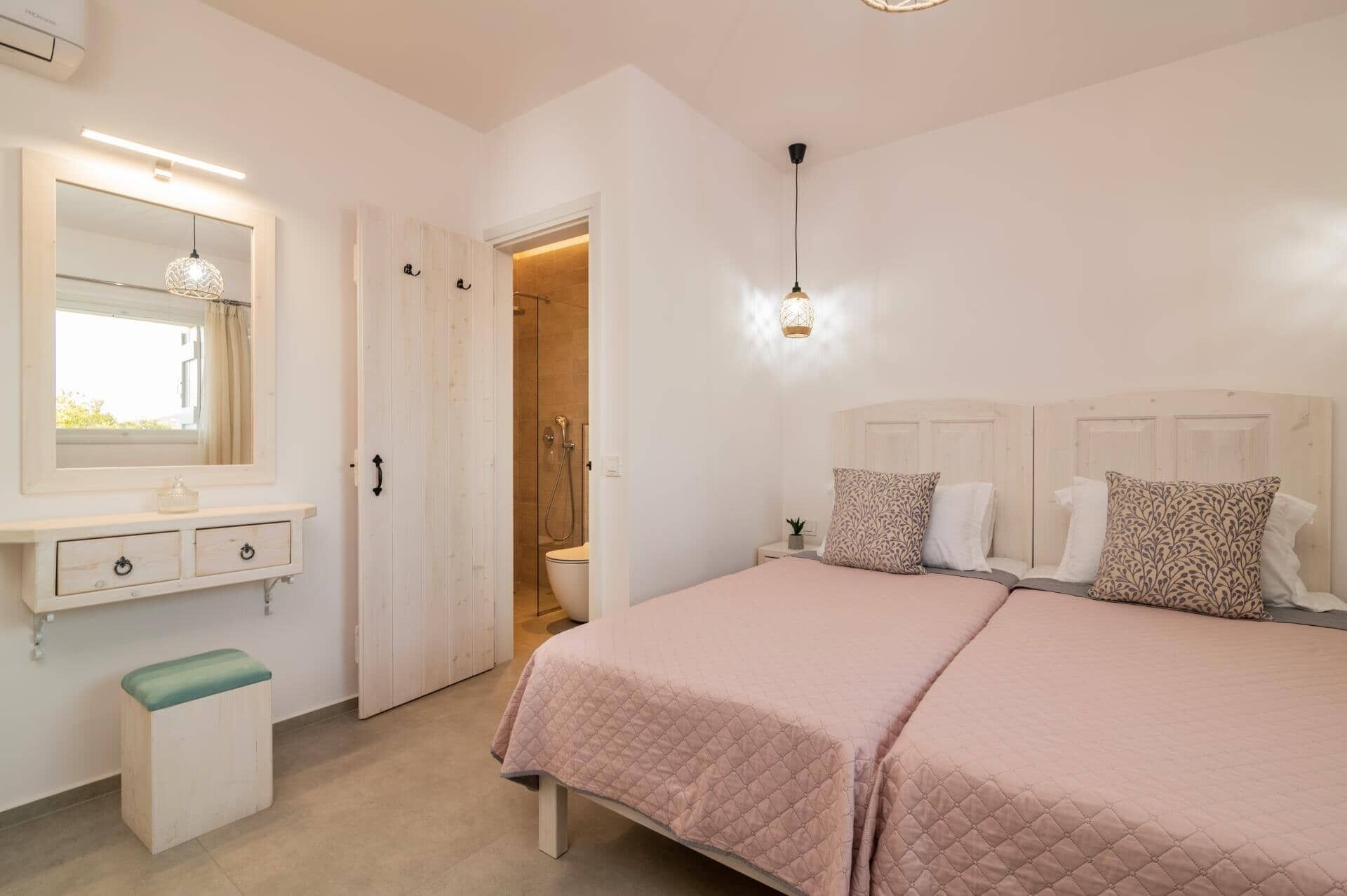 A bedroom with a bed, bedside table, mirror, and a door leading to a bathroom.