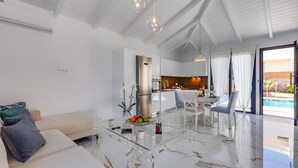 Ein modernes Wohnzimmer mit einem Glastisch, einer Couch und einem Essbereich mit Blick auf einen Pool.