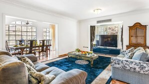 A living room with a sofa, a coffee table, a TV, and a dining area with chairs and a table. - Villa Paris by Villa Plus (Chayofa)