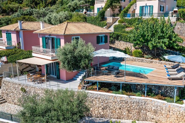 Une villa dotée d’une piscine, d’un espace salon extérieur et d’un mur en pierre.