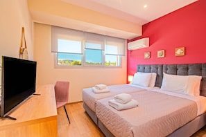 Quarto de hotel com uma cama, televisão e janela com vista para o campo.