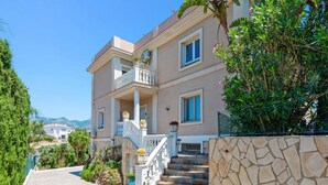 A two-story building with a balcony, stone steps, and surrounding greenery. - Villa Paraisos Sol by Villa Plus (Las Lagunas de Mijas)