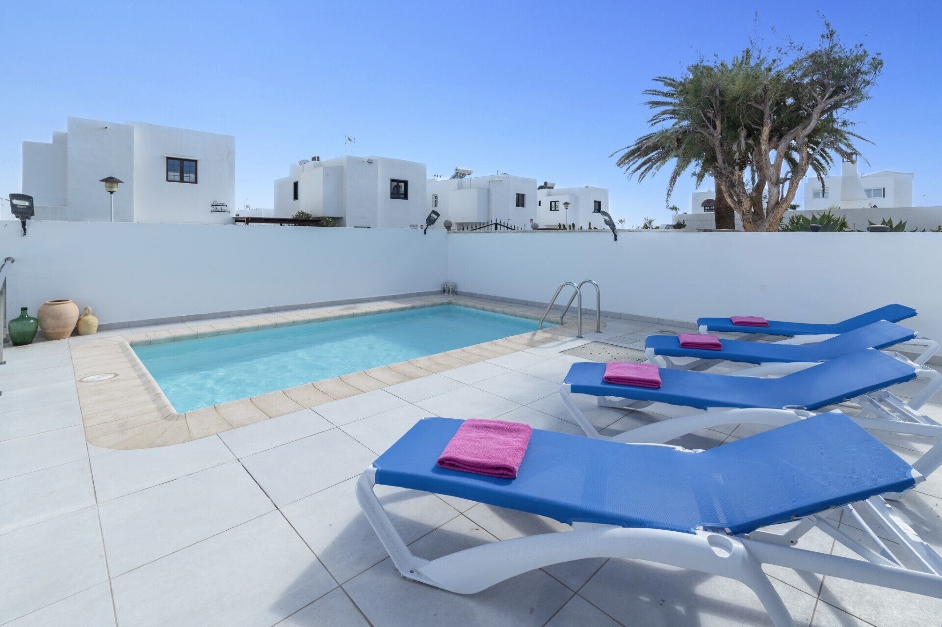 Un espace piscine aménagé sur le toit, avec des chaises longues bleues et une petite piscine.