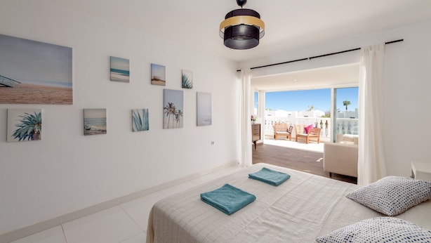 A bedroom with a bed, a ceiling fan, and artwork on the walls. - Villa Sunny Side by Villa Plus (Puerto del Carmen)