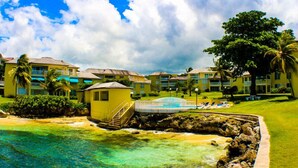 A resort with a pool, a small building, and multiple hotel rooms. - Sea Palms Holidays (Tower Isle)