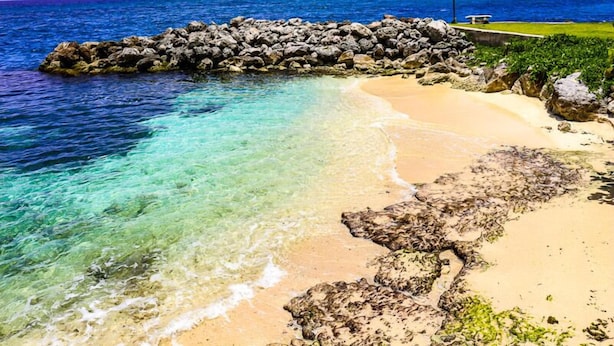 A beach with clear turquoise water, sandy shore, and a rocky breakwater. - Sea Palms Holidays (Tower Isle)