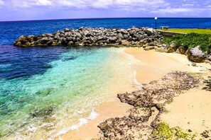 A beach with clear turquoise water, sandy shore, and a rocky breakwater. - Sea Palms Holidays (Tower Isle)