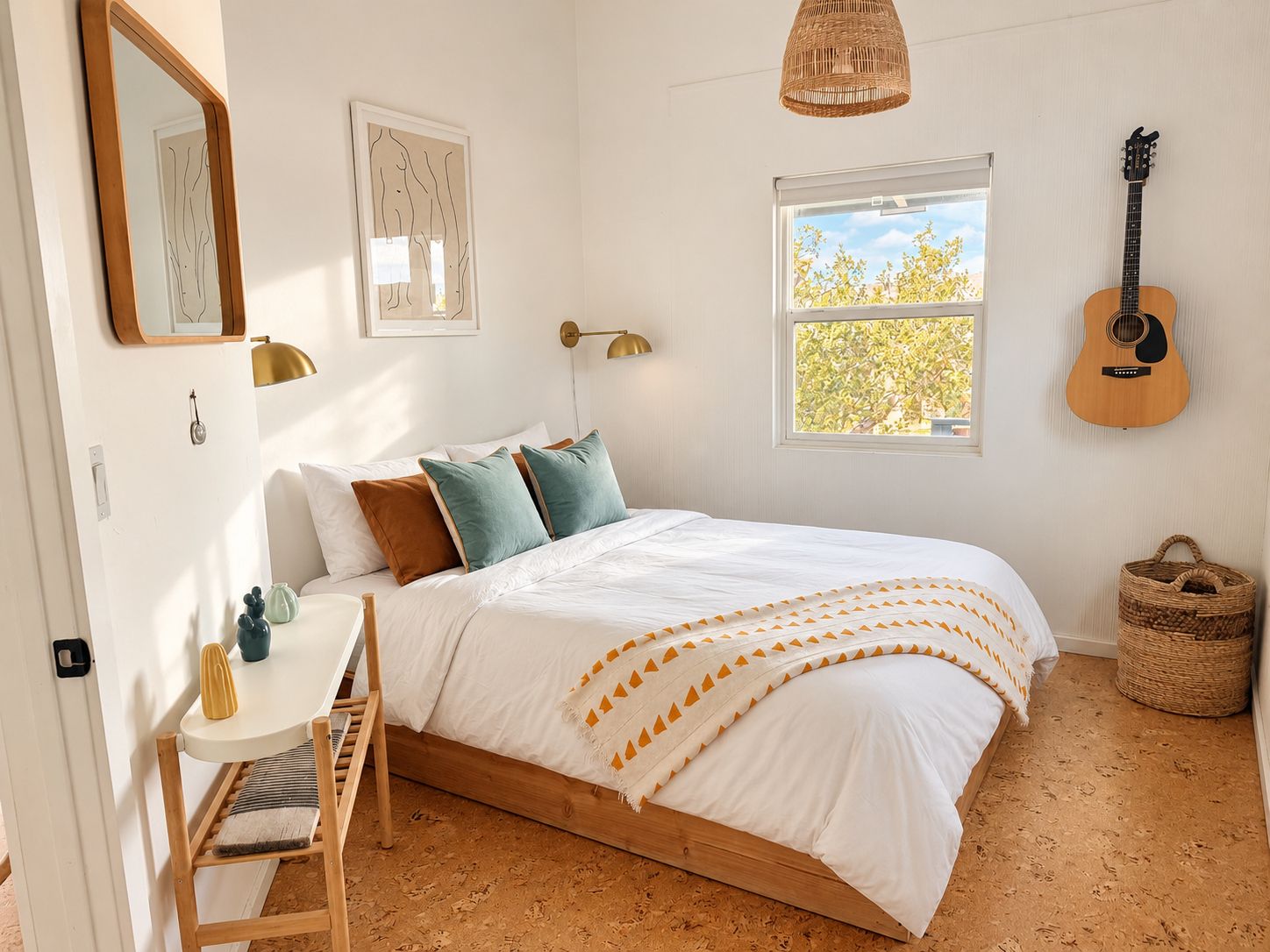 A bedroom with a bed, a desk, a chair, a guitar, and a window with a view of trees.