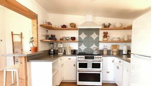 A compact kitchen with white cabinets, a built-in oven, and a coffee maker. - Joshua Tree - Under the Stars-Pool, Spa & Fire pit (Yucca Valley)