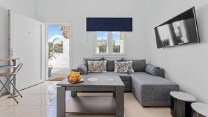 A modern living room with a grey sofa, a coffee table with fruit, and a TV on the wall. - Home2Book Charming Apartment Teguise, Terrace (Nazaret)