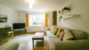 Una sala de estar con chimenea de piedra, un sofá, una mesa de centro y un televisor.