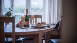 A dining table with a bottle of champagne, two glasses of orange juice, and croissants.