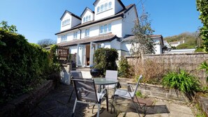A two-story house with a patio area featuring a table and chairs.
