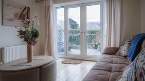 A living room with a sofa, a round table, and a potted plant.