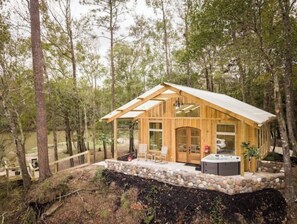 Une cabane en bois avec des fondations en pierre, de grandes fenêtres et un jacuzzi.