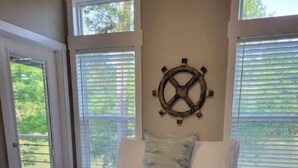 Un dormitorio con una cama grande, una decoración de rueda de barco y vistas a través de las ventanas.