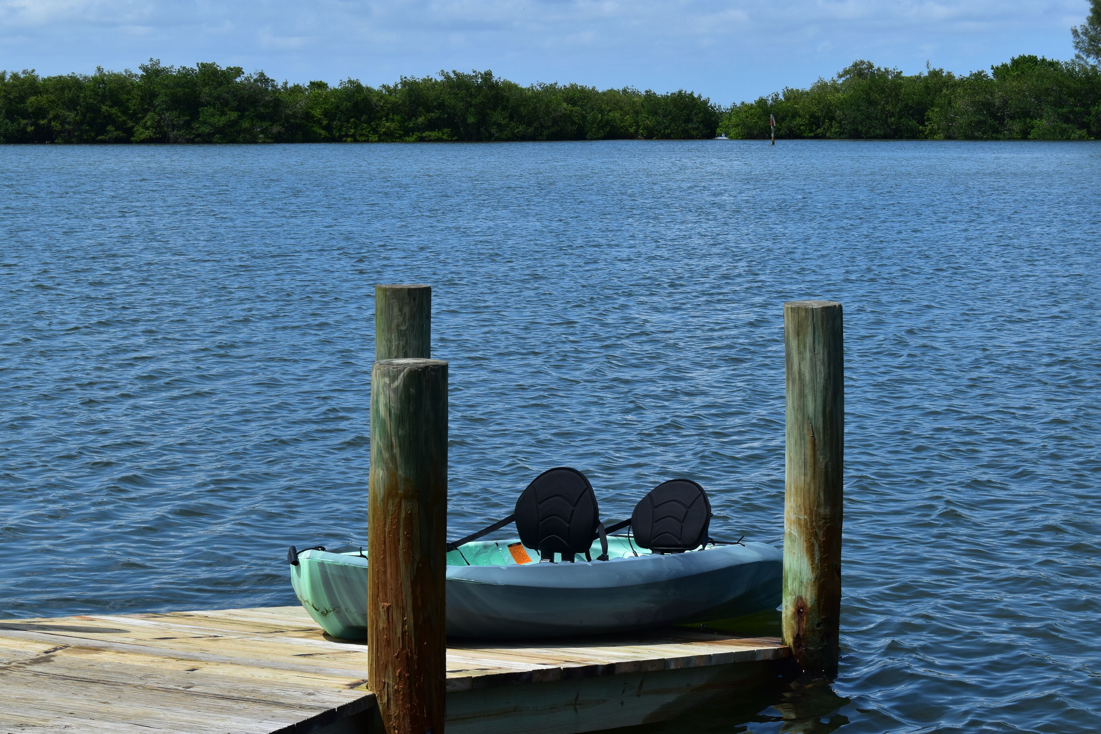 A kayak with two paddles on a wooden dock extending into a calm lake.