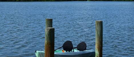 A kayak with two paddles on a wooden dock extending into a calm lake.
