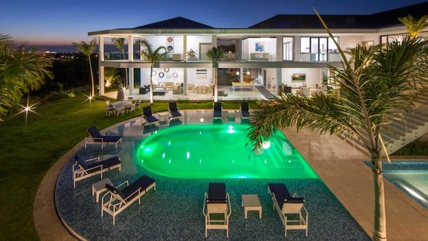 A modern two-story house with a swimming pool, lounge chairs, and a well-maintained lawn. - Casa de Campo’s Ultimate Group Villa Pool, Cinema & Pickleball (La Romana)